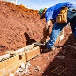 Trabalhador da construção civil atua na fundação de uma obra ao ar livre.