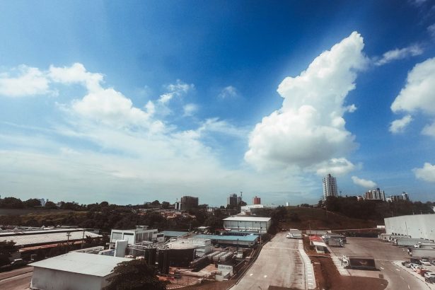 Vista aérea de uma área industrial moderna, com galpões e vias em meio à paisagem urbana.