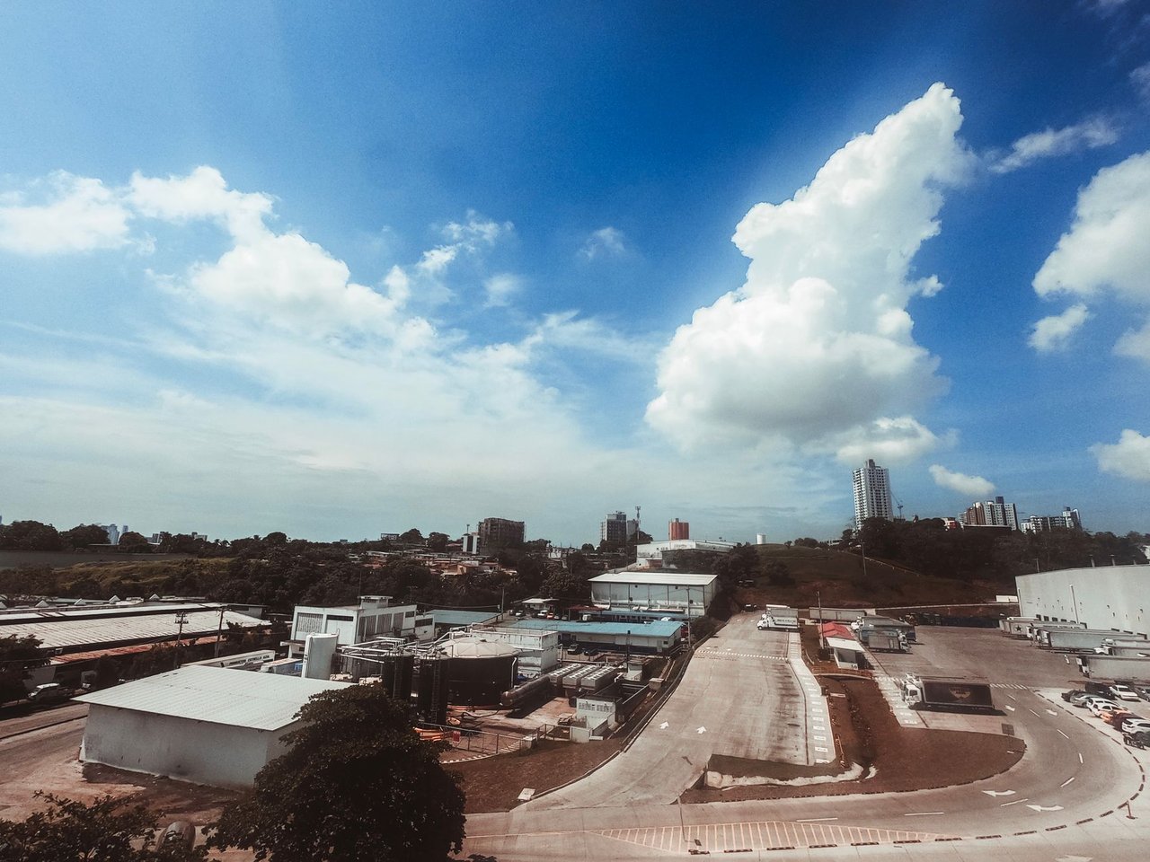Vista aérea de uma área industrial moderna, com galpões e vias em meio à paisagem urbana.
